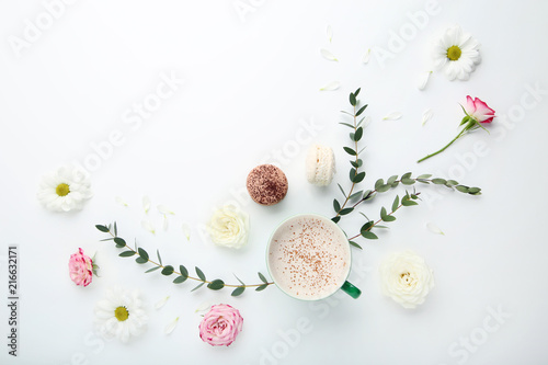 Flowers with cup of coffee and macarons on white background