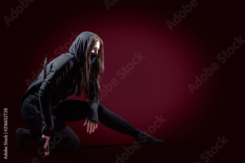 Canvas Print Beautiful samurai woman warrior with a sword in studio on red dark background