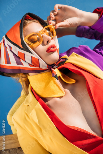 elegant charming woman posing in yellow sunglasses and colorful clothes