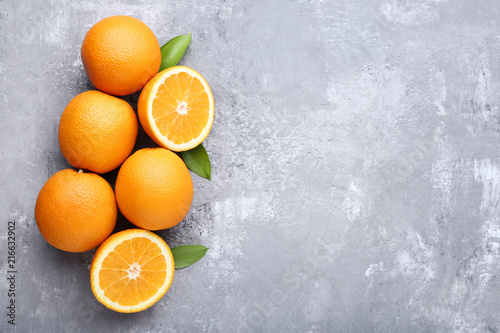 Orange fruit with green leafs on grey wooden table