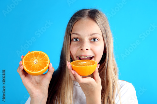 Young smiling girl with orange fruit on blue background