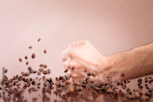 Closeup of hands with falling coffee beans on the table
