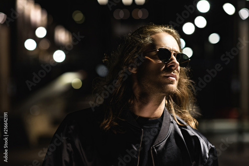 close-up portrait of attractive young man in sunglasses and leather jacket on city street at night © LIGHTFIELD STUDIOS