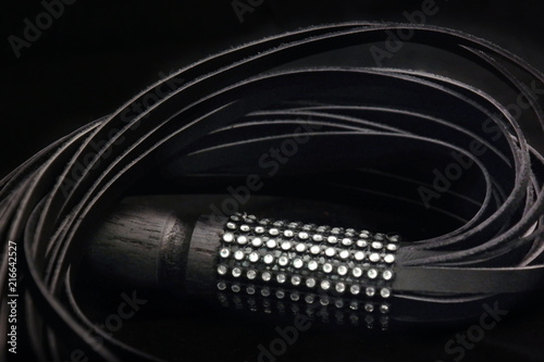 Black leather whip on a black background
