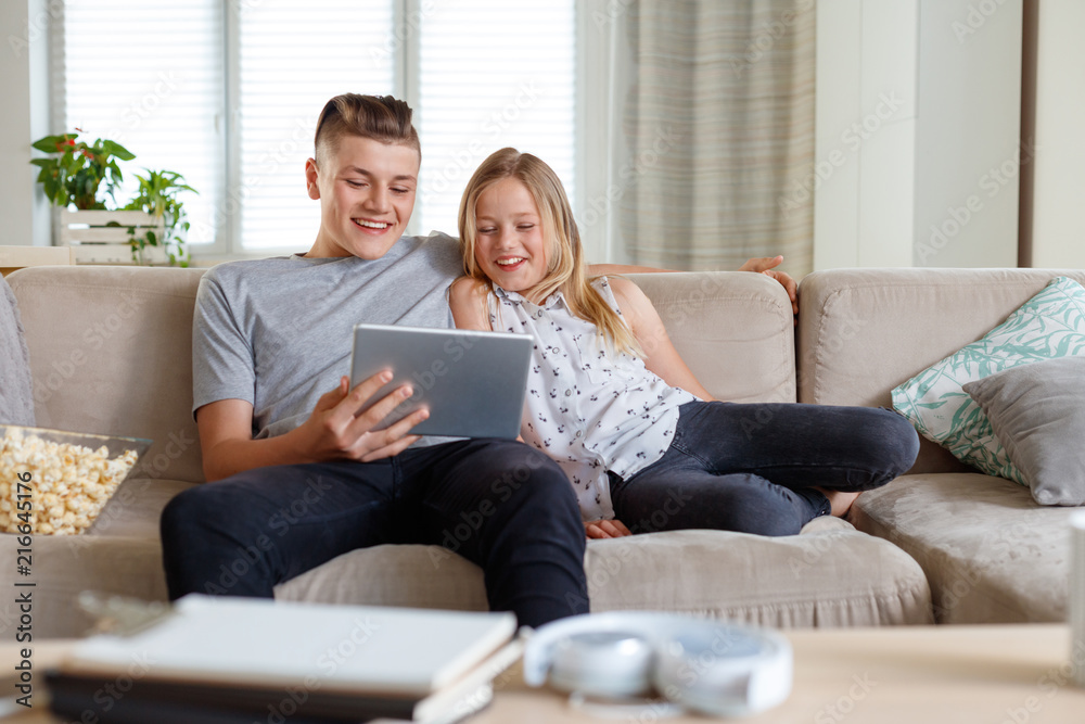 Siblings using a digital tablet together at home Siblings using a digital tablet together at home