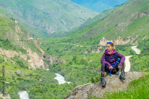 Young woman in the mountains with a backpack. Mountain landscape. River in the valley.