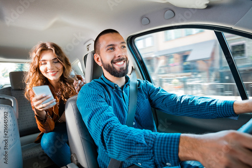 Fototapeta Uber driver sitting in a car with female passenger