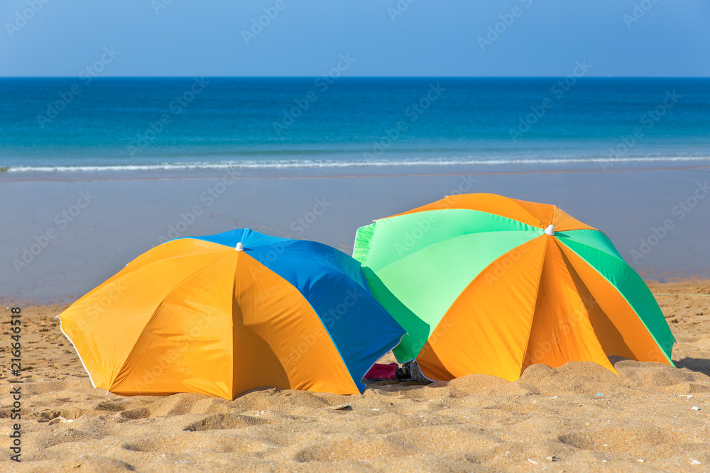 Two colorful parasols on beach by the sea
