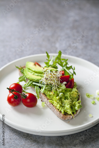 Rye toast with avocado  tomatoes and alfalfa sprouts