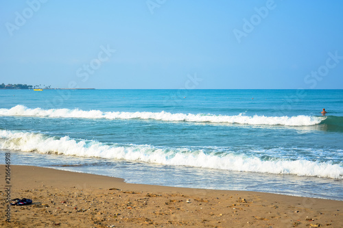 The sea sandy beach in the early morning  on the sea  among the waves  a man is bathing.