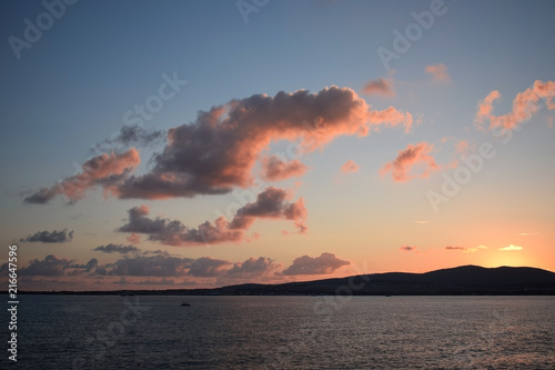 Sunset over the sea. The Sun sets behind the mountains