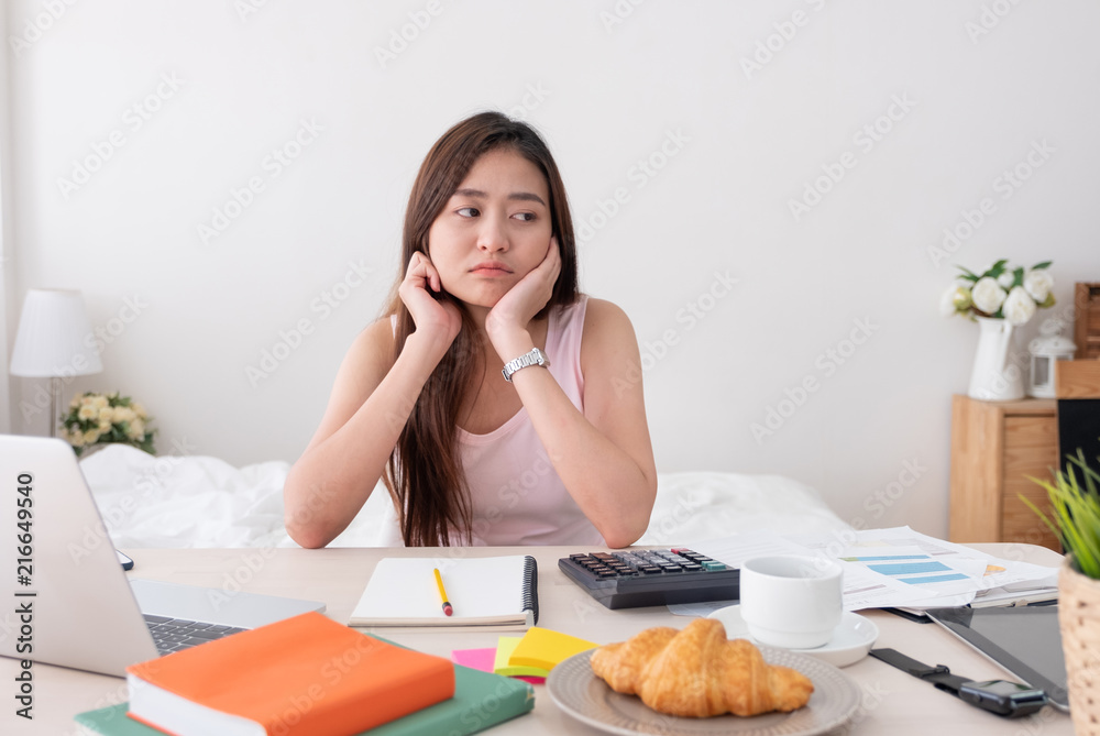 Asian woman freelancer rest chin on hand with bore feeling with work problem with laptop on mess table.work at home concept.stress working. Asian woman freelancer rest chin on hand with bore feeling with work problem with laptop on mess table.work at home concept.stress working.