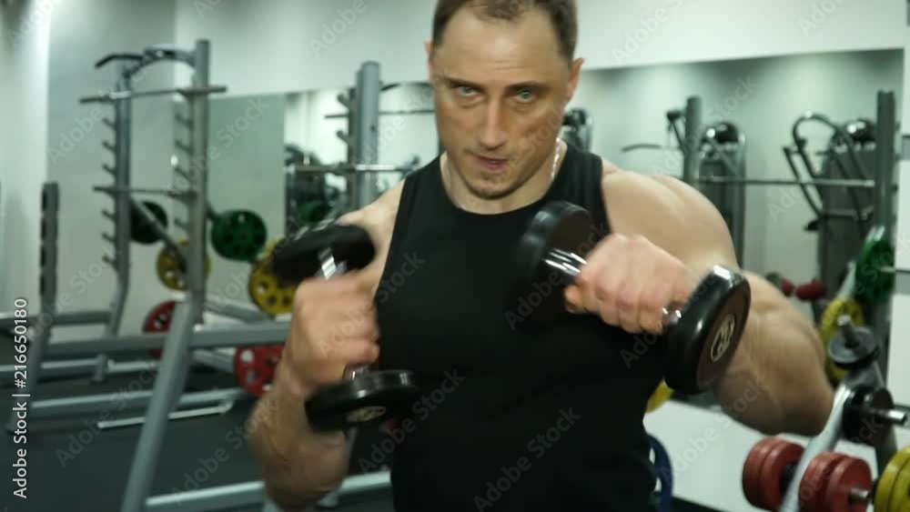 A muscular boxer with dumbbells in his hand is working out blows. A muscular boxer with dumbbells in his hand is working out blows.