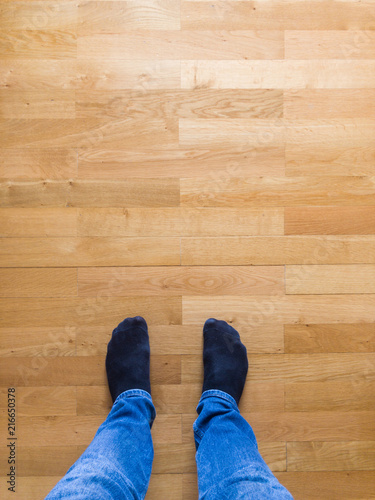 Man in jeans and socks standing on wooden floor
