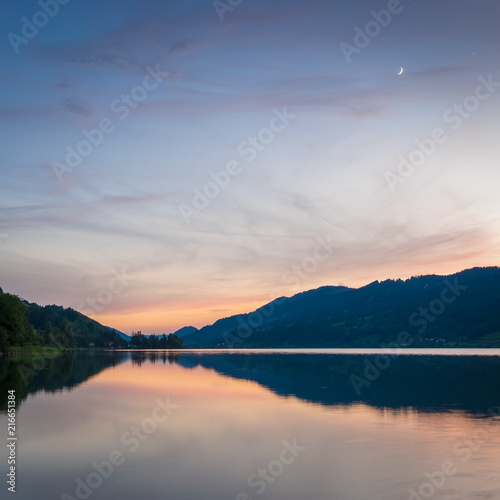 Mondsichel   ber dem See in den Bergen am Abend