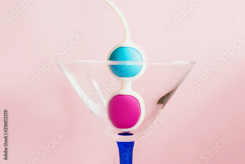 Color Kegel balls in a triangle cocktail glass. Concept of women health photo