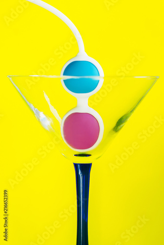 Color Kegel balls in a triangle cocktail glass. Concept of women health photo