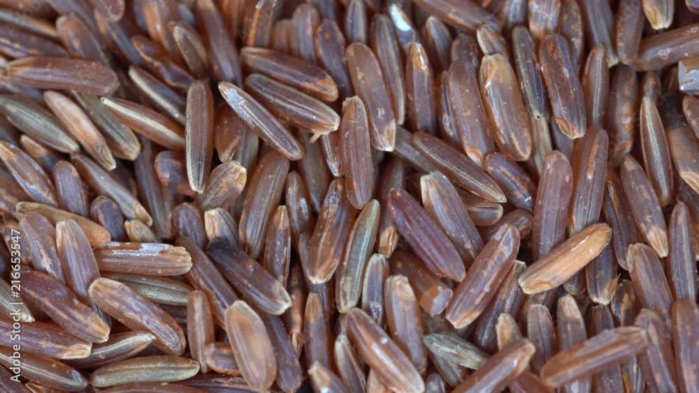 Pile of unpolished brown rice background, close up rotation loopable 4k top view. Food  background. Gastronomy concept, organic food. Macro organic rice