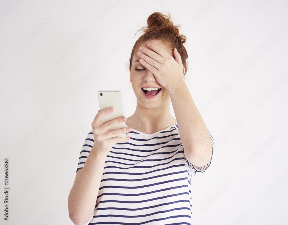 Girl using mobile phone and laughing at studio shot Girl using mobile phone and laughing at studio shot