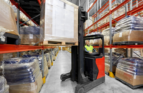 logistic business  shipment and loading concept - loader operating forklift with cargo at warehouse