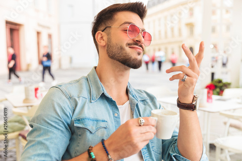 portrait of proud man with sunglasses having a coffee outside