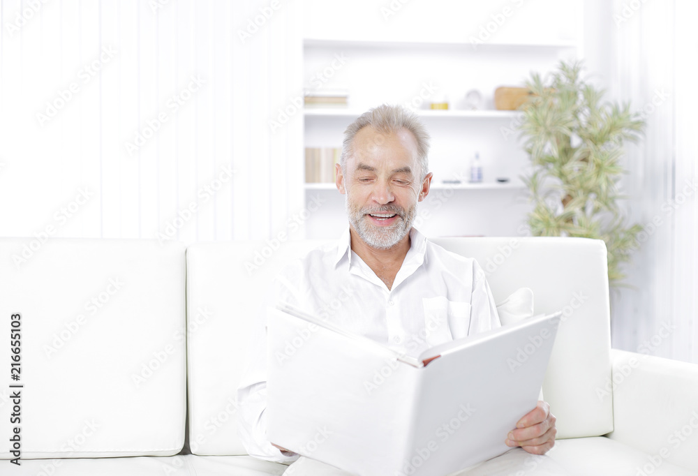 Smiling senior man reading file folder on the couch Smiling senior man reading file folder on the couch