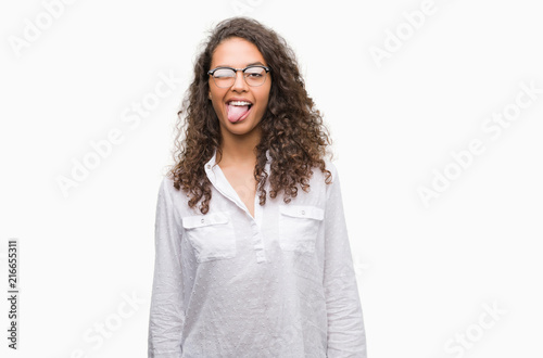 Beautiful young hispanic woman sticking tongue out happy with funny expression. Emotion concept.