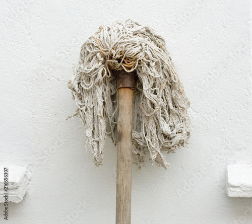 Mop resting against a white wall