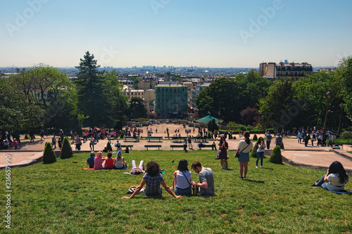 Paris, France-MAY 06, 2018: View from the Montmartre hill to the green lawn in front of the Sacre Coeur church with tourists relaxing and enjoying sunny weather while looking over Paris