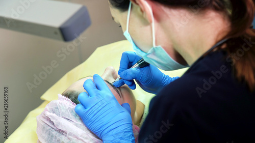 Cosmetologist applying permanent tattooing of eyebrows in beauty salon closeup. Modern microblading workflow and permanent makeup. Beauty  wellness and healthcare concept
