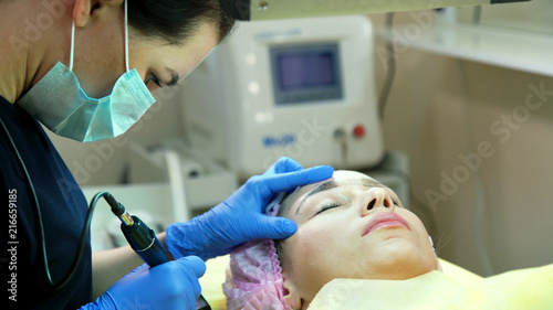 Cosmetologist applying permanent tattooing of eyebrows in beauty salon closeup. Modern microblading workflow and permanent makeup. Beauty, wellness and healthcare concept