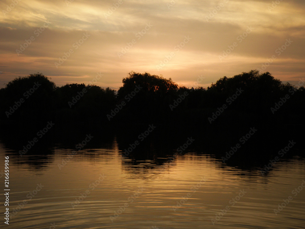 Obraz premium Colorful Sunset with tree silhouette reflecting at the lake