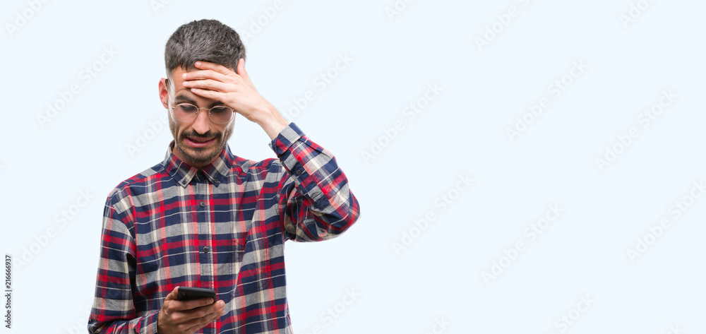 Young hipster adult man holding smartphone stressed with hand on head, shocked with shame and surprise face, angry and frustrated. Fear and upset for mistake. Young hipster adult man holding smartphone stressed with hand on head, shocked with shame and surprise face, angry and frustrated. Fear and upset for mistake.