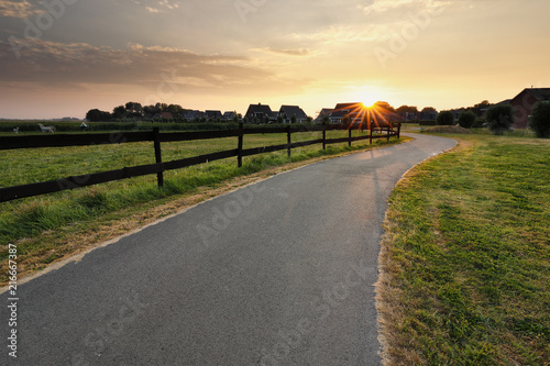 sunshine over cycling path by wooden fence photo
