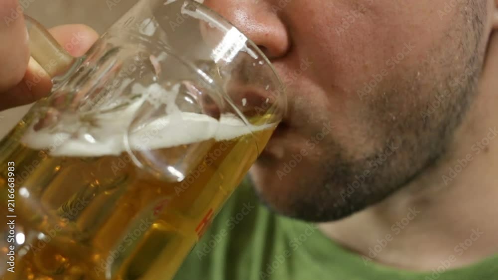 A white man chews something and drinks wheat beer, it is very tasty. Close-up, indoors, side view A white man chews something and drinks wheat beer, it is very tasty. Close-up, indoors, side view