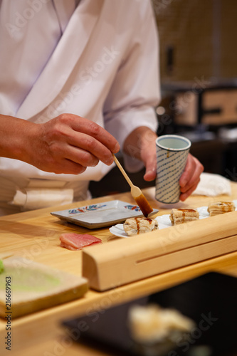 Professional and experienced sushi chef carefully add final touch with confident and dedication to his perfect sushi. Precision and Finesse at its best practice to achieve top performance in business.