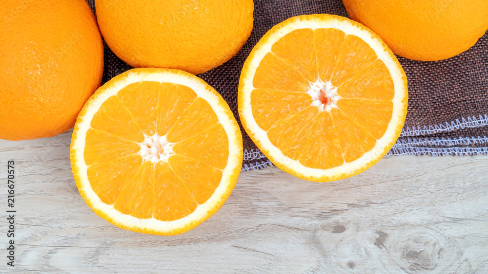Oranges fruit in a basket on a wooden table.