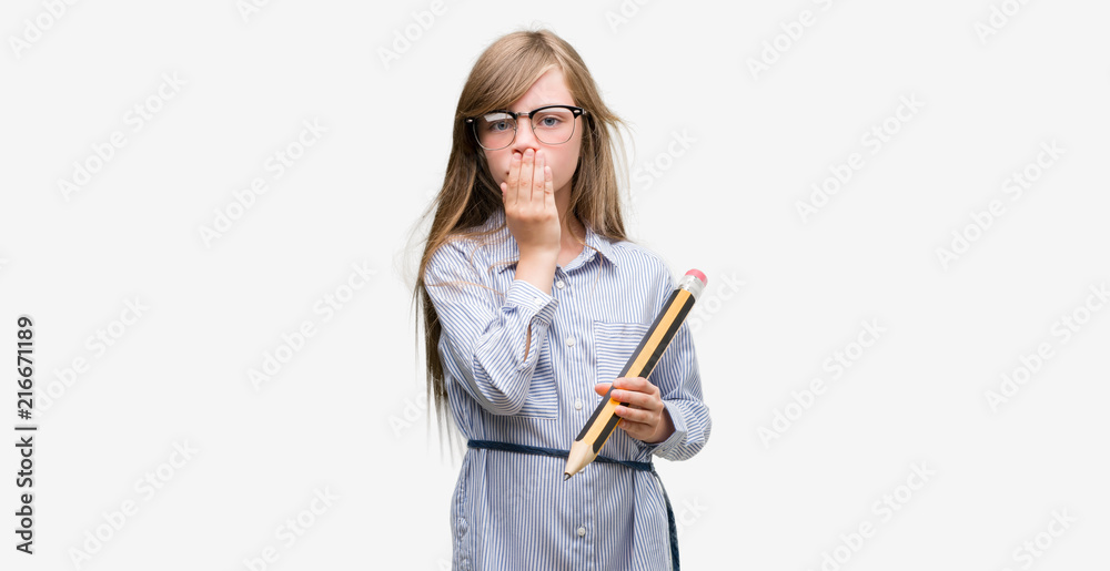 Young blonde child holding big pencil cover mouth with hand shocked with shame for mistake, expression of fear, scared in silence, secret concept Young blonde child holding big pencil cover mouth with hand shocked with shame for mistake, expression of fear, scared in silence, secret concept