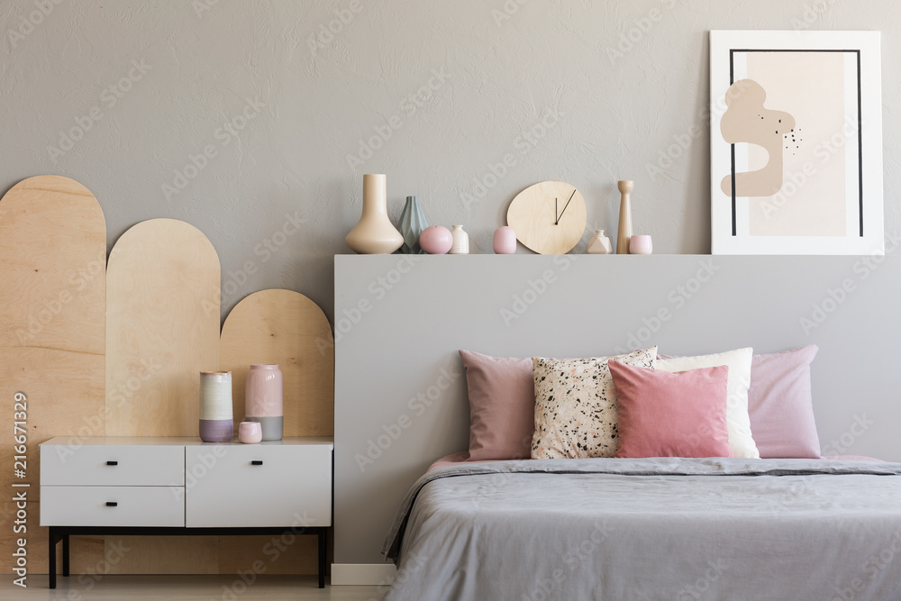 Pink pillows on grey bed in modern bedroom interior with poster and cabinet. Real photo - obrazy, fototapety, plakaty 