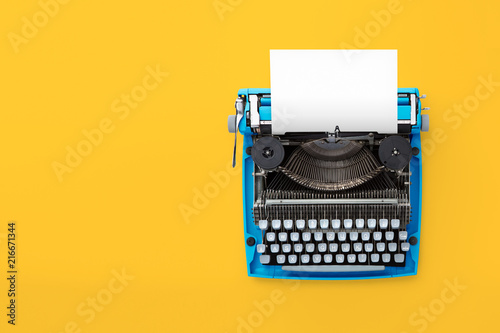 Typewriter machine in retro style on yellow background. Top view.