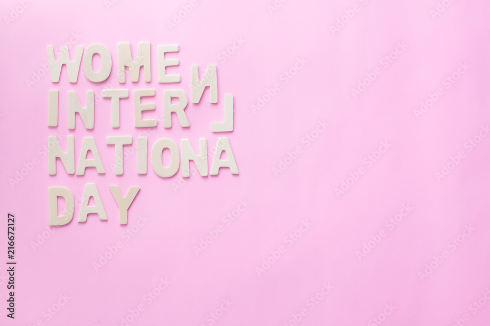 Text Wooden letter design with date of International Women's Day on pink background.