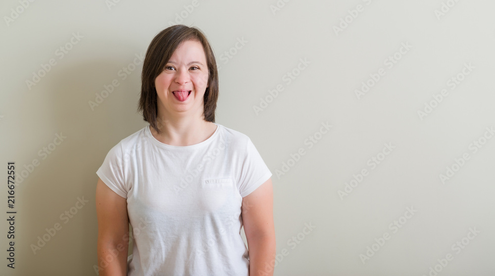 Down syndrome woman standing over wall sticking tongue out happy with funny expression. Emotion concept. Down syndrome woman standing over wall sticking tongue out happy with funny expression. Emotion concept.