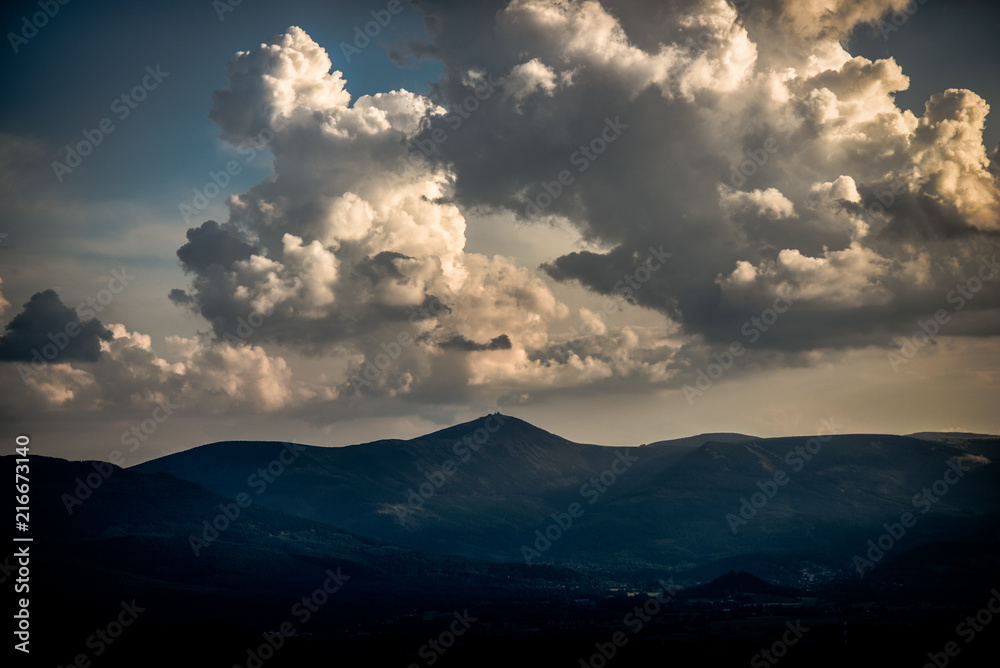 Beautiful clouds with the sun penetrating them during sunset over the Karkonosze Mountains.