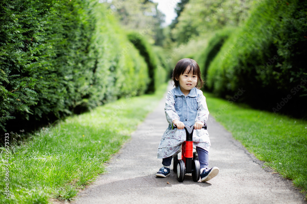 baby girl play bike in Summer forest park baby girl play bike in Summer forest park