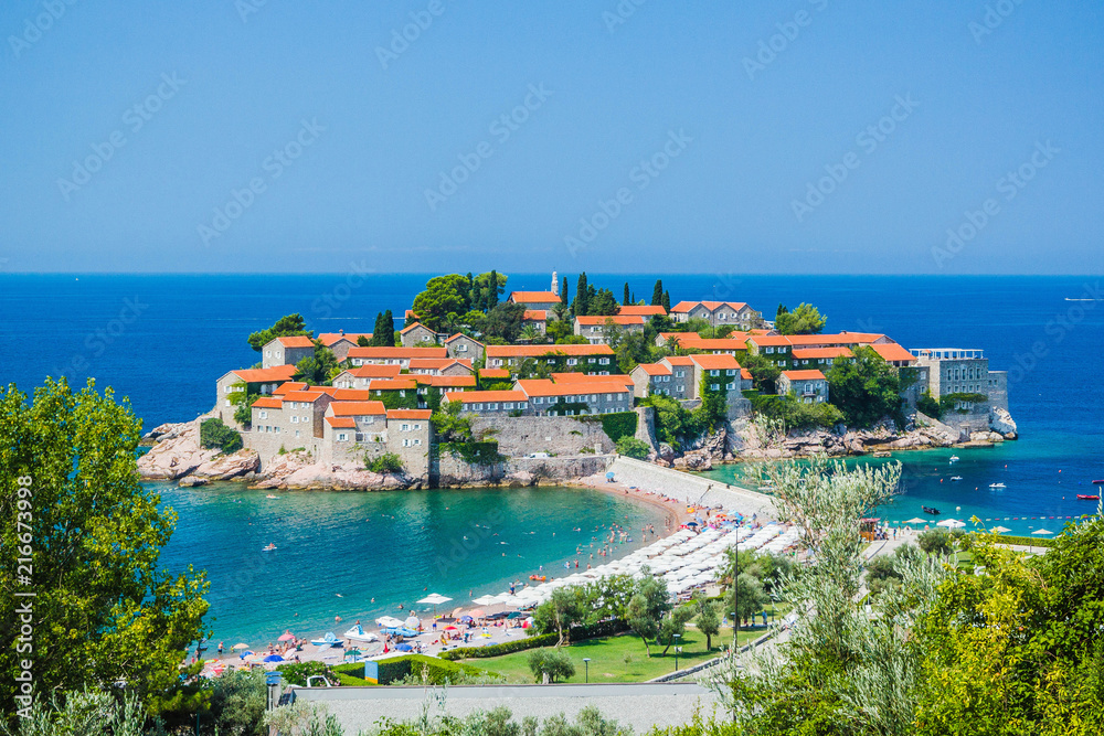 Panoramic view of island of Sveti Stefan, on old stone houses with red tiled roofs on clear summer sunny day, Budva, Montenegro, Adriatic Sea, Balkans