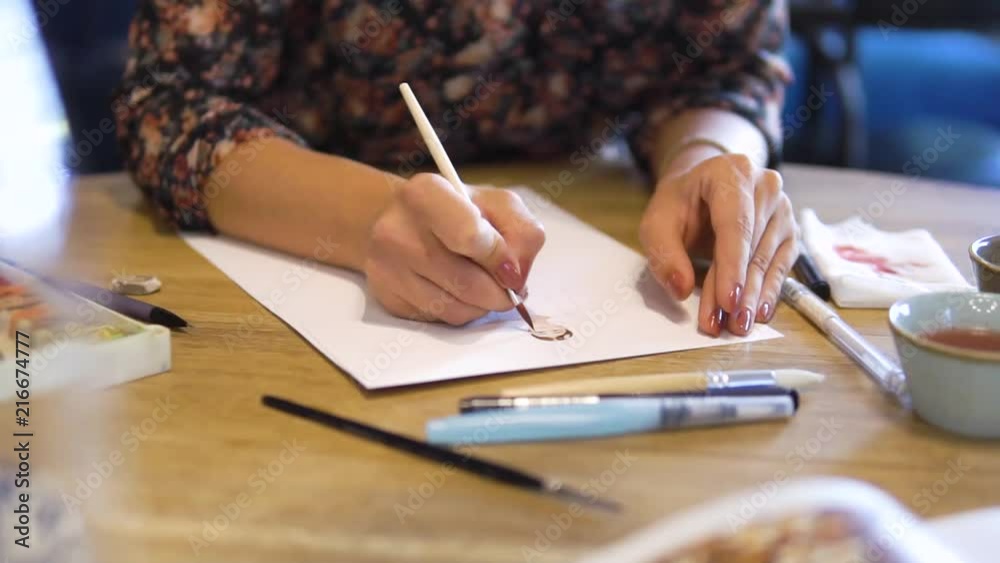 women's hands draw sketches on paper with a brush. A fashion designer or tailor, animator, artist or Illustrator women's hands draw sketches on paper with a brush. A fashion designer or tailor, animator, artist or Illustrator