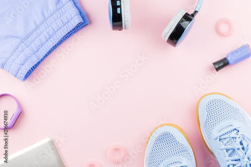 Woman sneakers, headphones, fitness tracker and running clothes on pastel background. Sport fashion concept. Flat lay