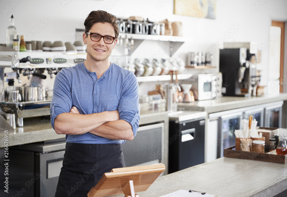 Fototapeta premium Male coffee shop owner behind the counter, arms crossed