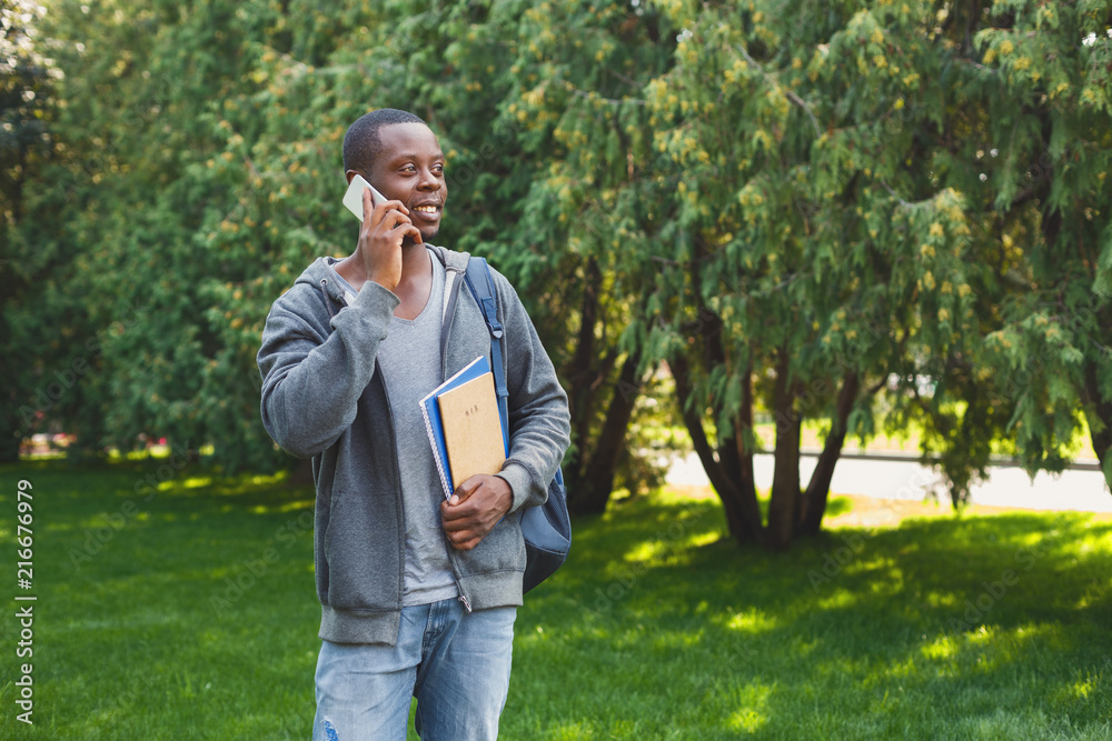 Happy african-american student talking on smartphone in the park