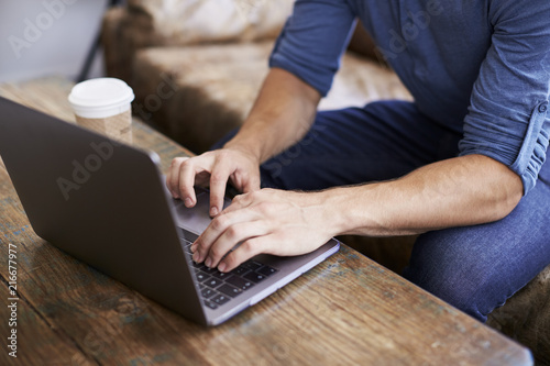 Young man using laptop in a coffee shop, mid section